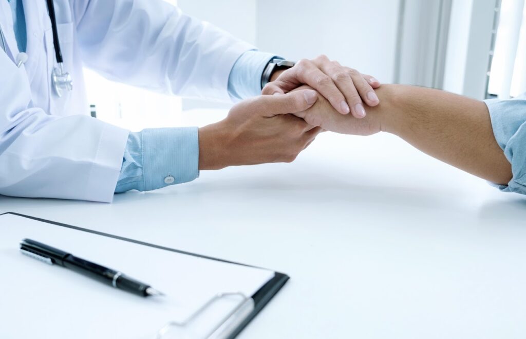 Una profesional sostiene las manos de otra persona en una consulta