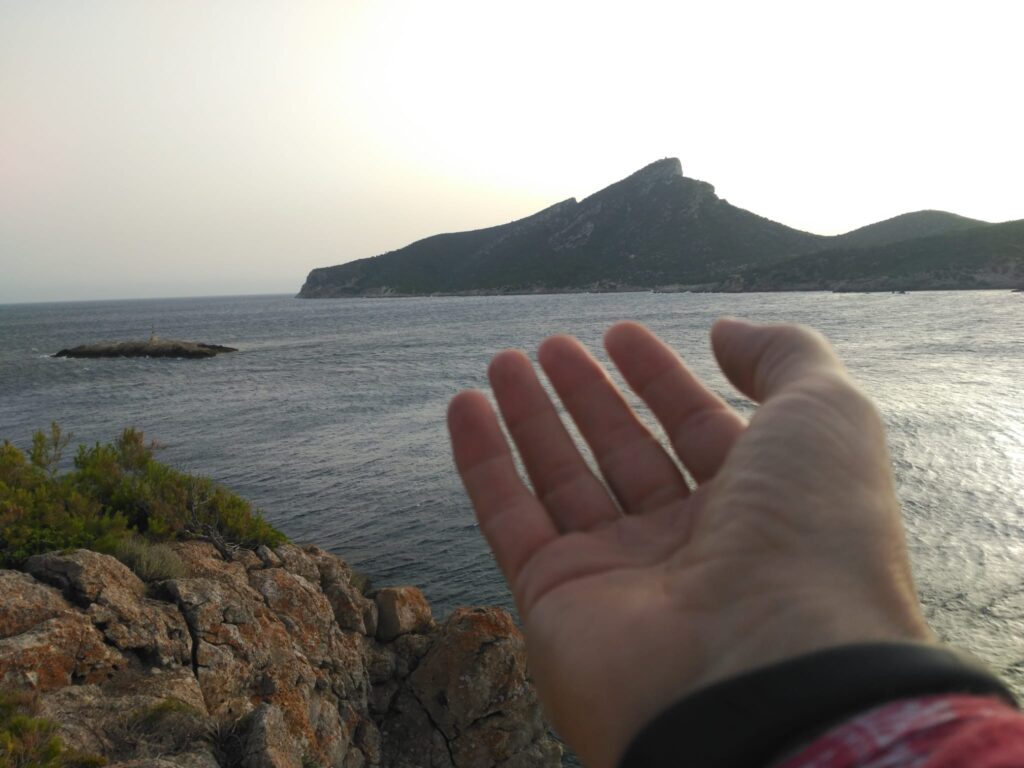 Mano abierta frente al mar y la costa de Mallorca
